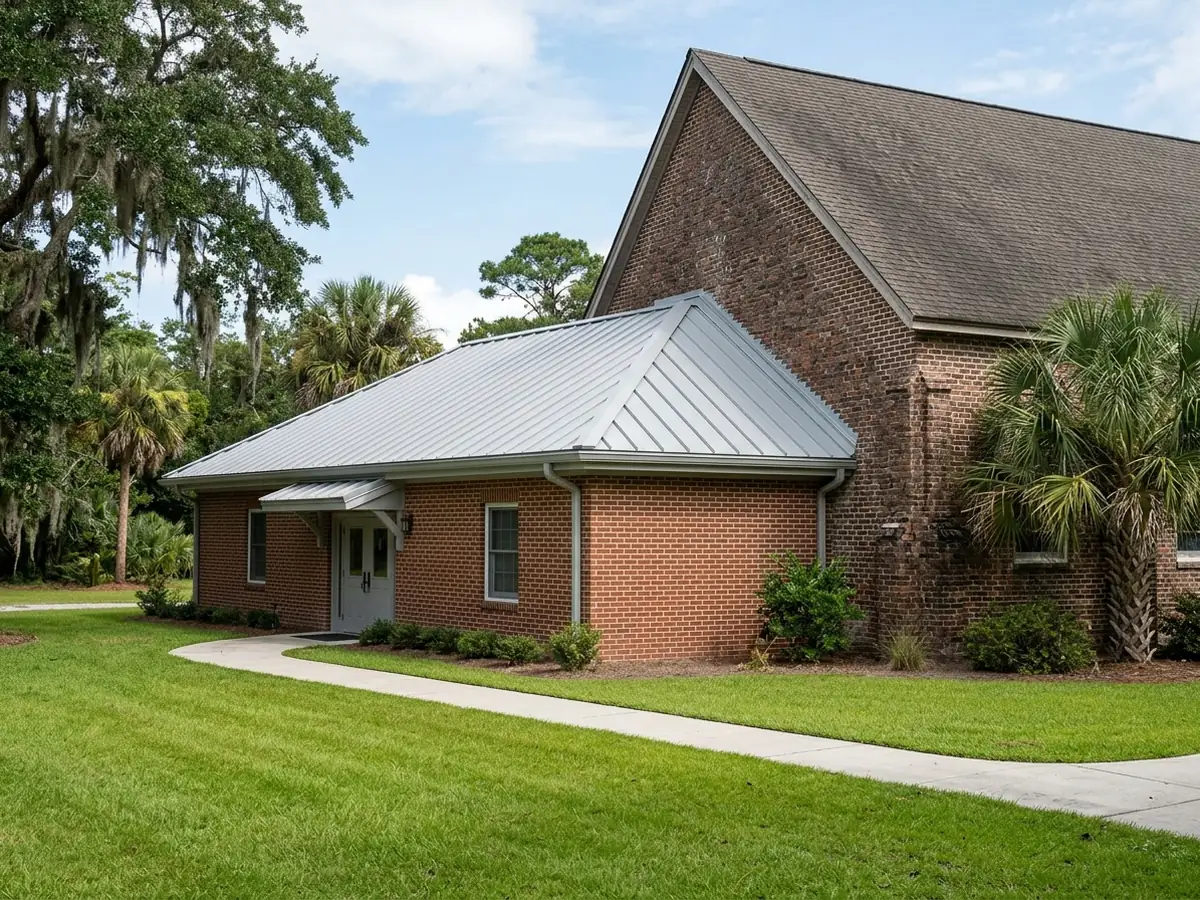 Low-slope standing seam metal roof on a single-storey church fellowship hall connected to a taller brick sanctuary