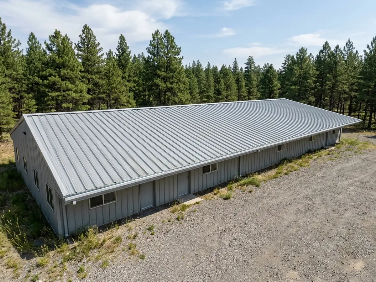 Long low metal building with a grey ribbed PBR panel roof showing tall trapezoidal ribs in straight lines